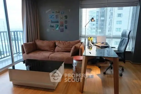 Modern living room with cozy sofa and sleek desk, featuring large windows and city view.