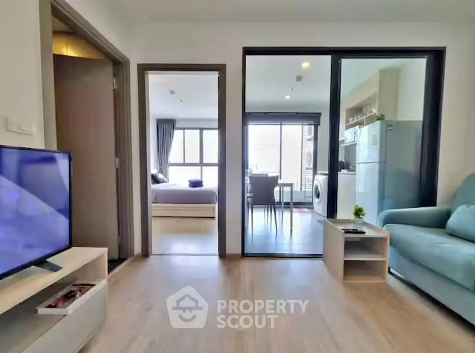 Modern apartment interior with open living room and kitchen, featuring sleek furniture and natural light.