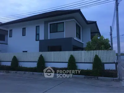 Modern two-story house with sleek design and fenced yard in suburban neighborhood.
