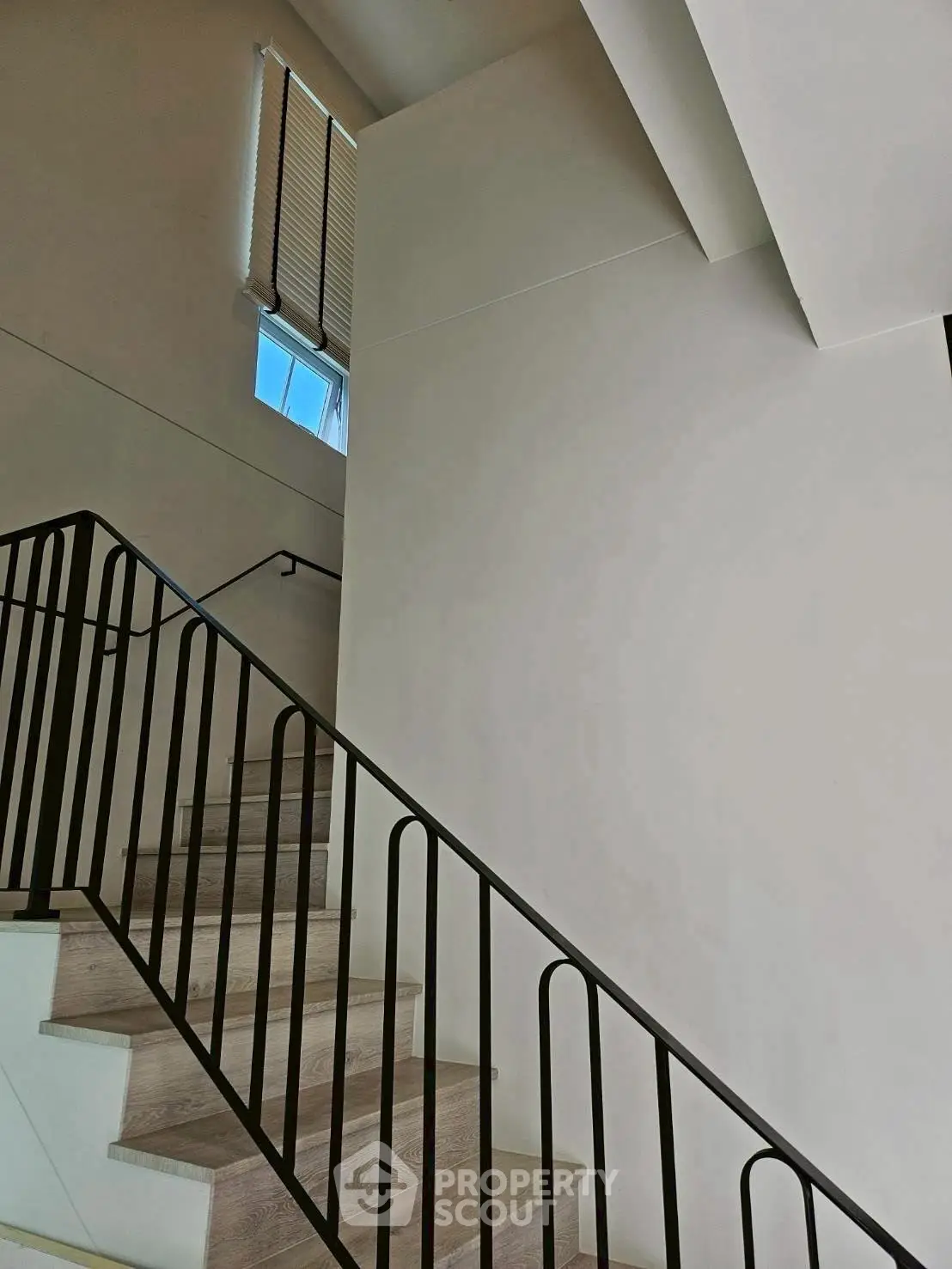 Modern staircase with sleek metal railing and natural light from window