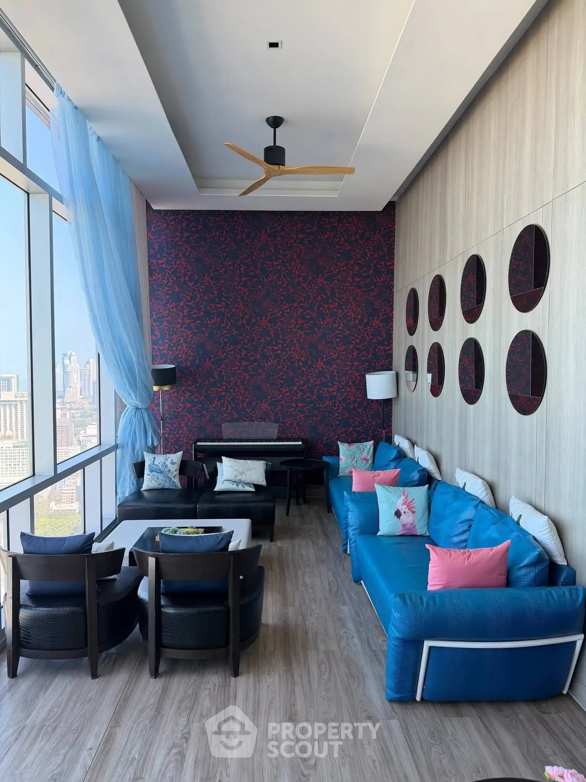 Luxurious living room with stunning city view, modern decor, and vibrant blue sofa in high-rise apartment.