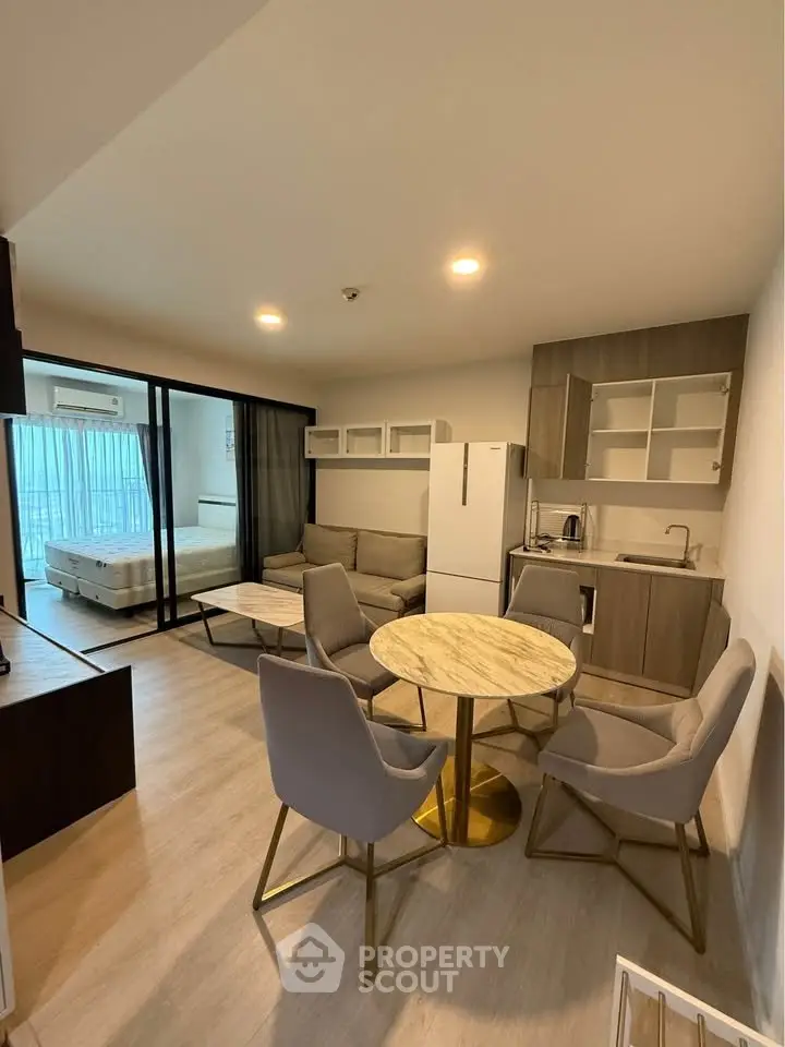Modern open-plan living room with kitchen and dining area, featuring sleek furniture and natural light.