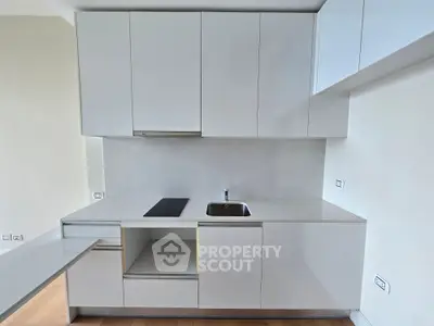 Modern minimalist kitchen with sleek white cabinetry and integrated appliances.