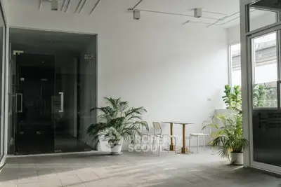 Modern minimalist lobby with glass doors and potted plants, ideal for welcoming guests.