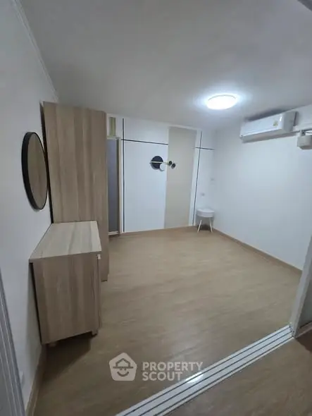 Minimalist room with wooden flooring and modern air conditioning unit, perfect for a cozy living space.
