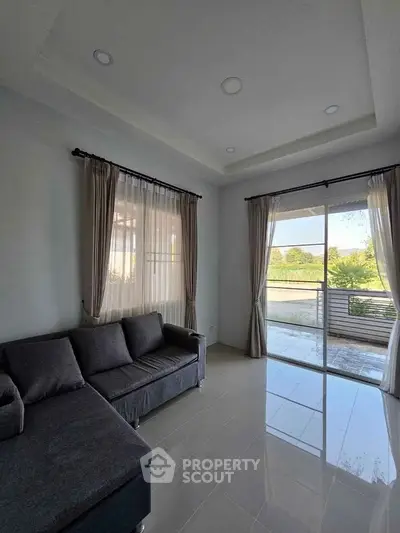 Bright living room with large windows and modern gray sofa, overlooking a serene outdoor view.