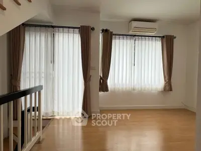 Bright and airy living room with large windows and elegant curtains, featuring a modern air conditioning unit.