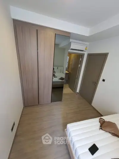 Modern bedroom with wooden flooring and built-in wardrobe, showcasing minimalist design and ample storage.
