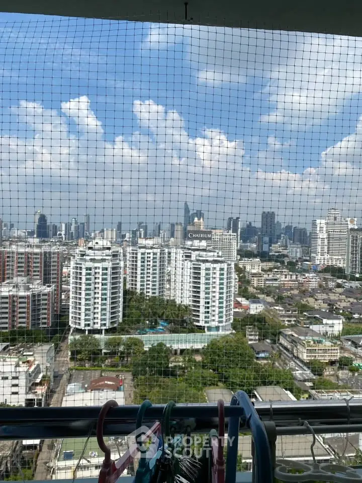 Stunning cityscape view from high-rise balcony with clear blue sky and urban skyline.