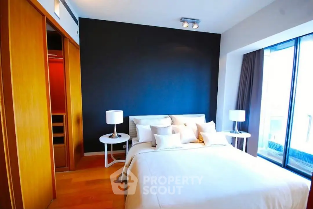 Modern bedroom with large window and stylish decor in a luxury apartment.