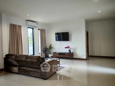 Spacious living room with modern decor and natural light, featuring a comfortable sofa and wall-mounted TV.