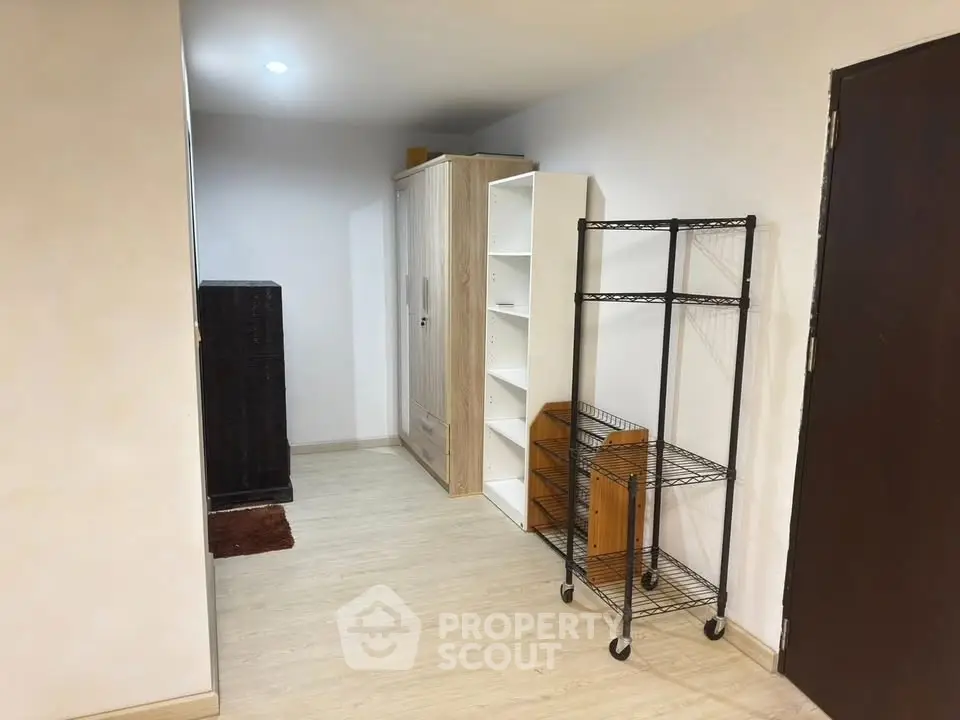 Spacious storage area with shelving units and wooden flooring in modern apartment.