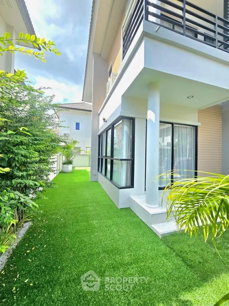 Modern house exterior with lush green artificial lawn and contemporary design.