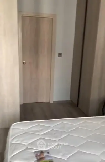 Cozy bedroom with wooden wardrobe and door, featuring a comfortable mattress.