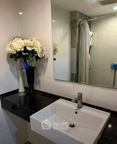 Modern bathroom with sleek sink, large mirror, and elegant floral decor.