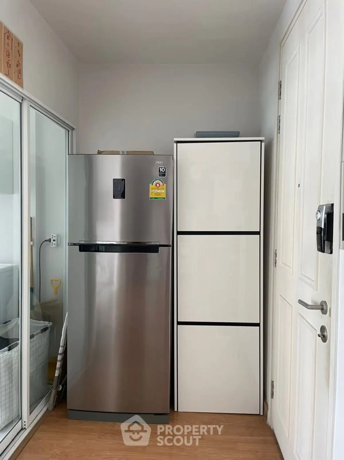 Modern kitchen corner with stainless steel fridge and sleek storage cabinet.