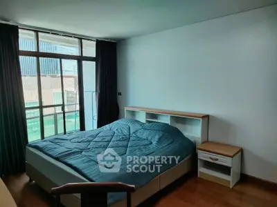 Spacious bedroom with large window and modern furnishings in urban apartment