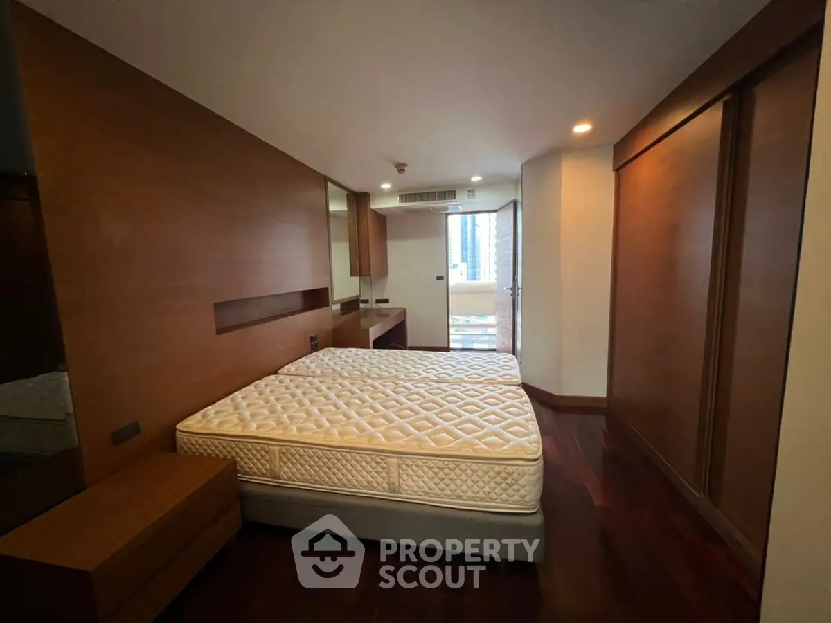 Spacious bedroom with wooden accents and balcony access in modern apartment.