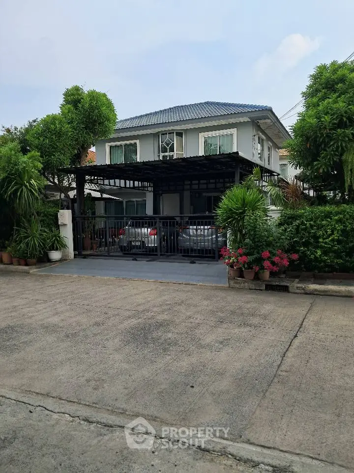 Charming two-story house with lush greenery and spacious driveway in a serene neighborhood.