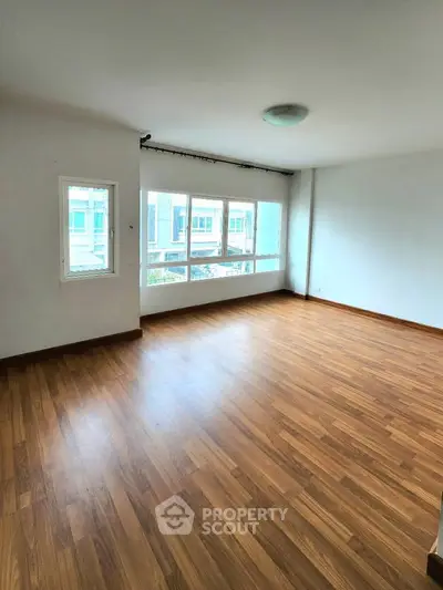Spacious empty room with large windows and wooden flooring, perfect for customization.