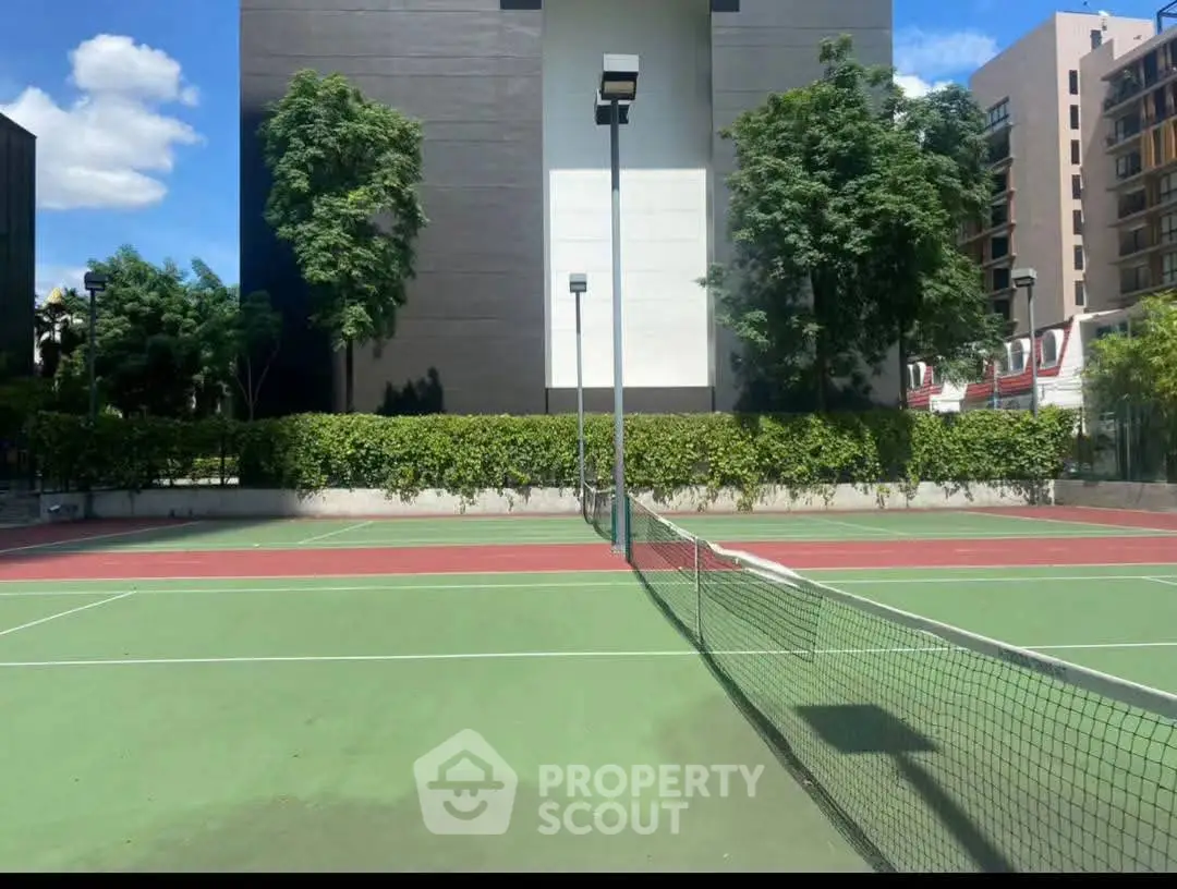 Modern apartment building with adjacent tennis court and lush greenery, perfect for active lifestyle seekers.