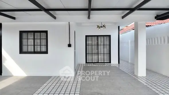 Modern minimalist exterior with sleek black and white design, spacious tiled area.
