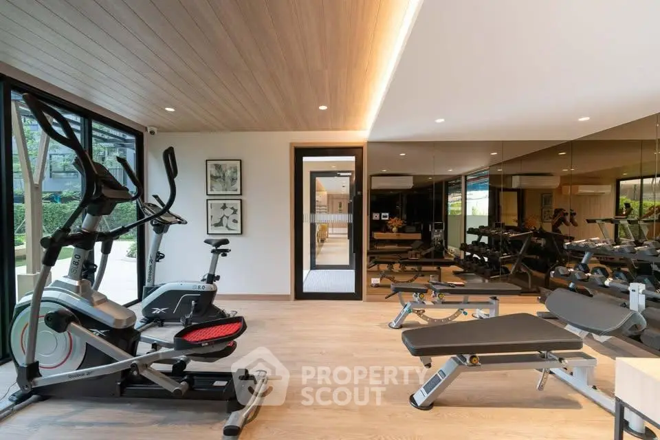 Modern gym with state-of-the-art equipment and mirrored walls in luxury residential building.