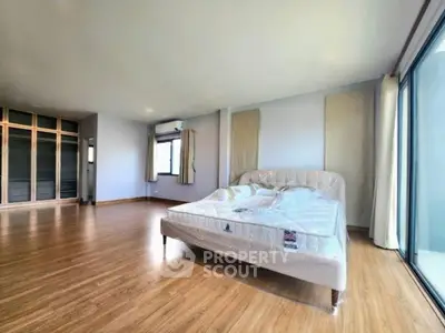 Spacious bedroom with wooden flooring and large windows in modern apartment
