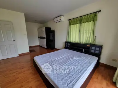 Spacious bedroom with wooden flooring and large window, featuring a modern bed and air conditioning.