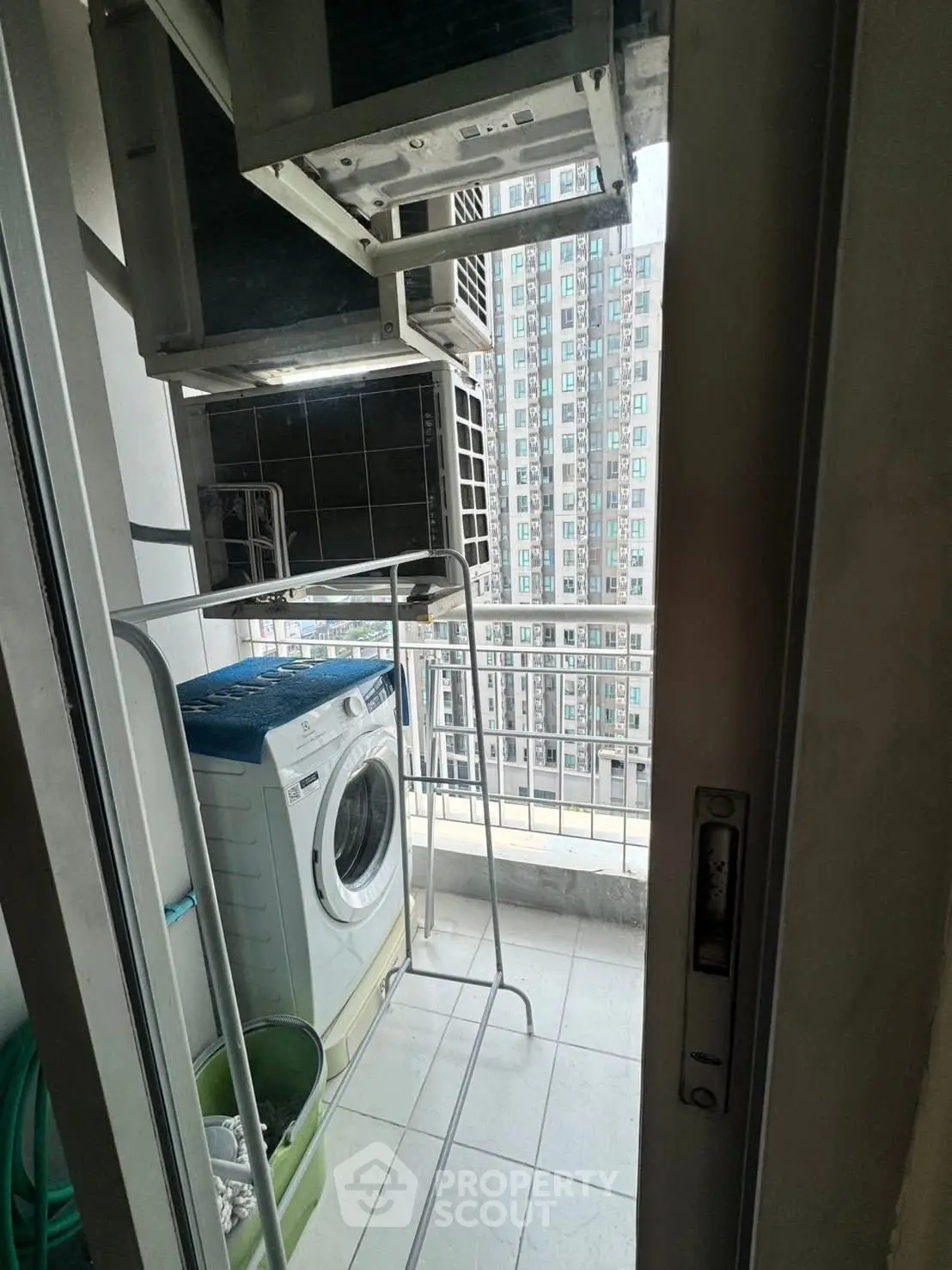 Compact balcony with washing machine and city view, ideal for urban living convenience.