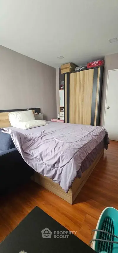 Cozy bedroom with wooden flooring and modern wardrobe, perfect for relaxation and comfort.