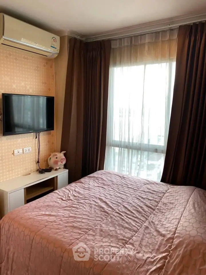 Cozy bedroom with natural light, featuring a wall-mounted TV and air conditioning for comfort.