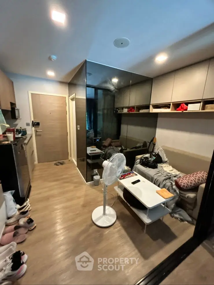 Modern living room with sleek design and mirrored wall, cozy seating area, and stylish decor.