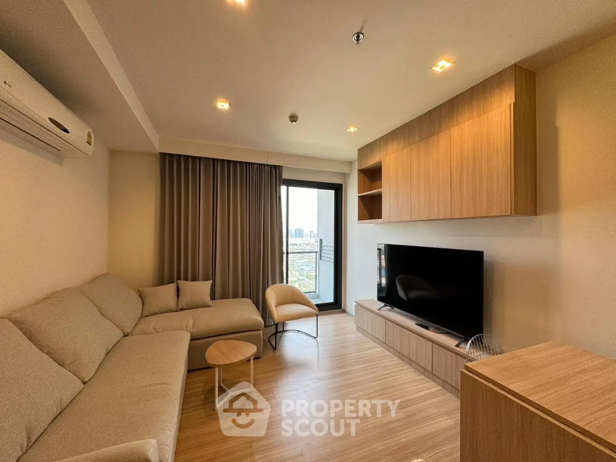 Modern living room with large TV, cozy sofa, and city view from window.