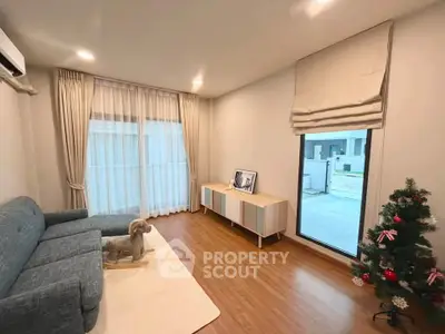 Modern living room with stylish decor, featuring a cozy sofa, elegant curtains, and a festive touch with a small Christmas tree.