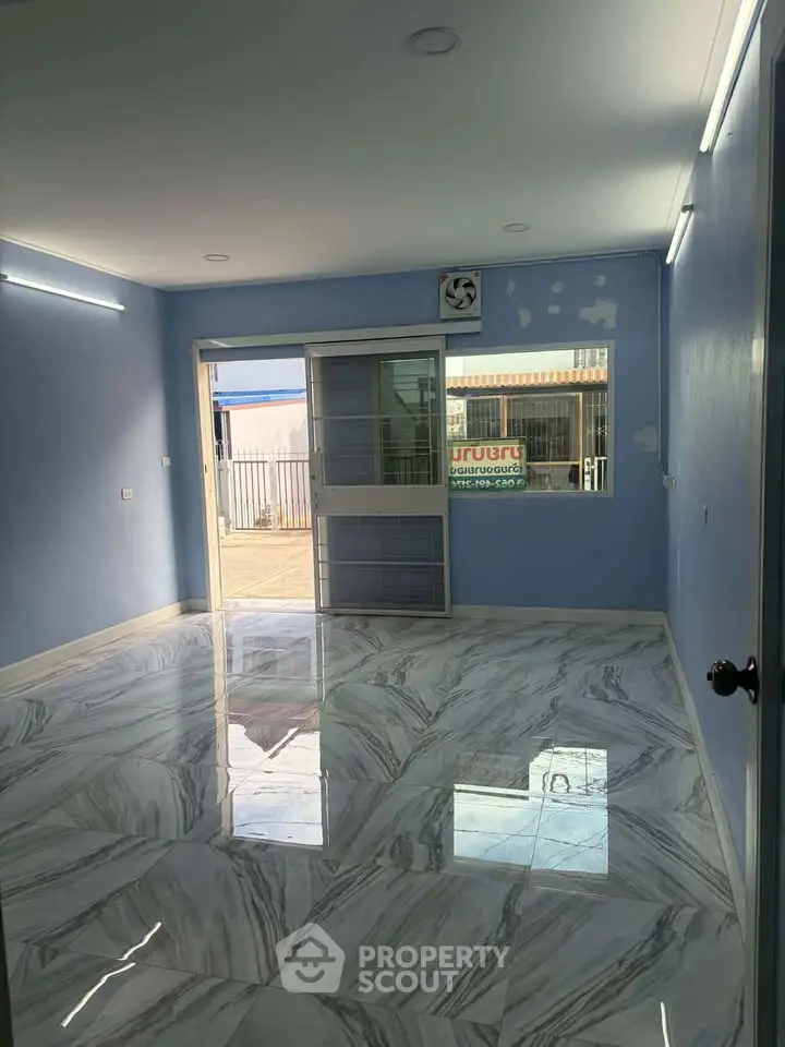 Spacious room with glossy marble flooring and large sliding glass door, perfect for versatile use.