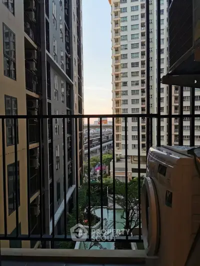 Modern apartment balcony with city view and washing machine, overlooking pool and high-rise buildings.