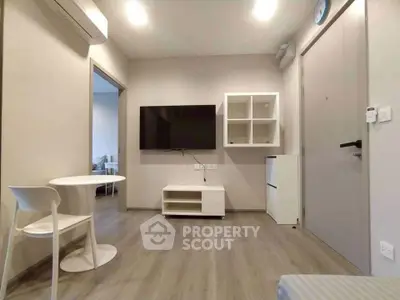 Modern living room with minimalist furniture and wall-mounted TV in a cozy apartment.