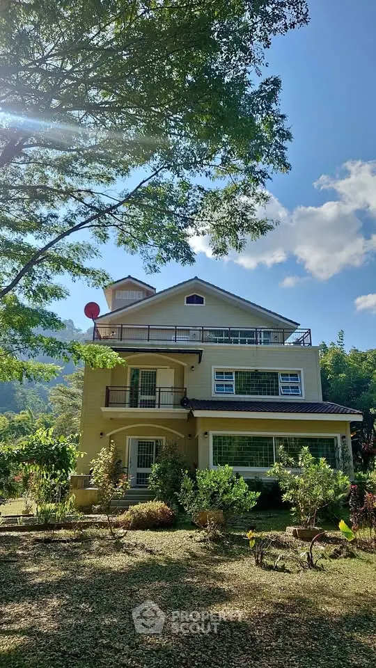 Charming multi-story house with lush garden and scenic mountain backdrop, perfect for serene living.