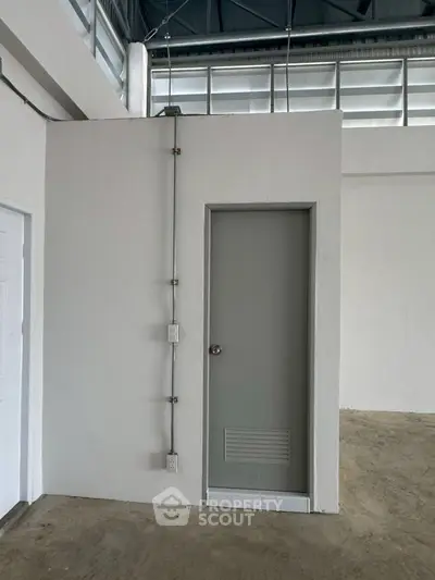 Minimalist industrial interior with small door and exposed wiring