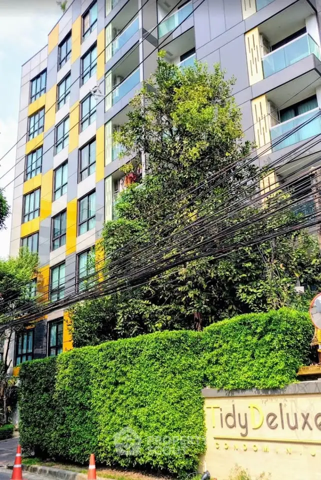 Modern apartment building with vibrant facade and lush greenery in urban setting.