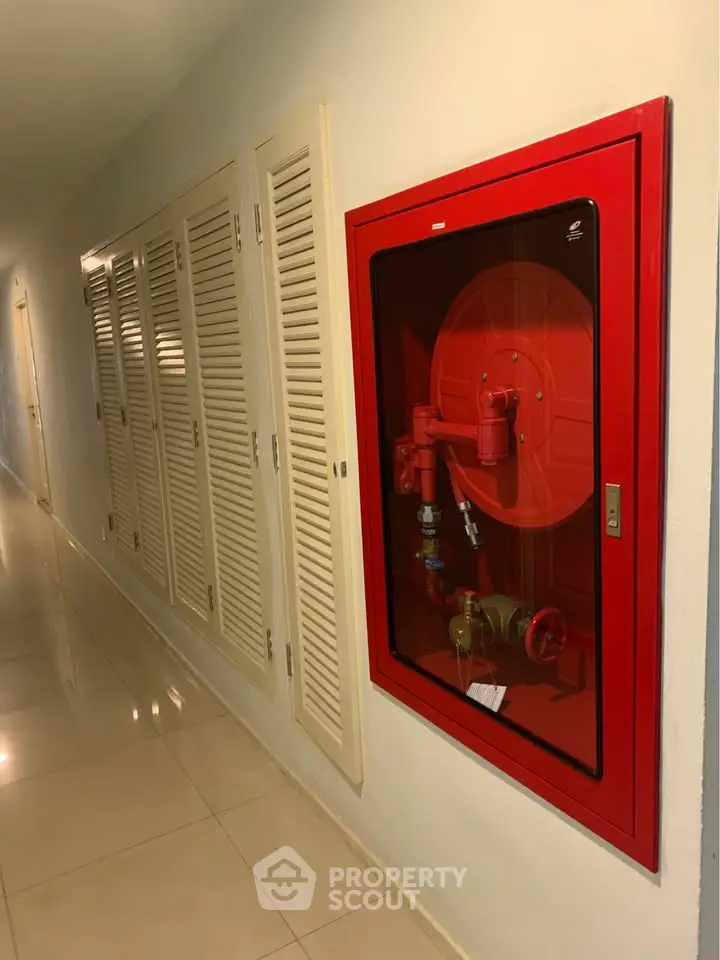 Modern building corridor with fire safety equipment and storage lockers.