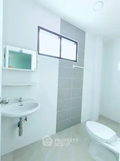 Modern bathroom with sleek design and natural light, featuring a stylish sink and toilet.