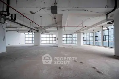 Spacious open-plan commercial space with large windows and industrial design, ideal for customization.