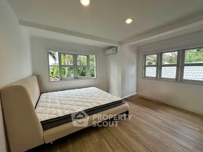 Spacious bedroom with large windows and natural light, featuring a comfortable bed and modern flooring.