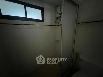 Compact bathroom with shower and window, ideal for efficient space use.
