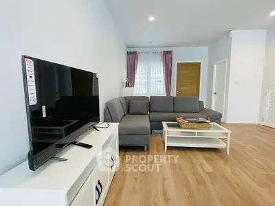 Spacious modern living room with sleek furniture and large TV, perfect for relaxation.