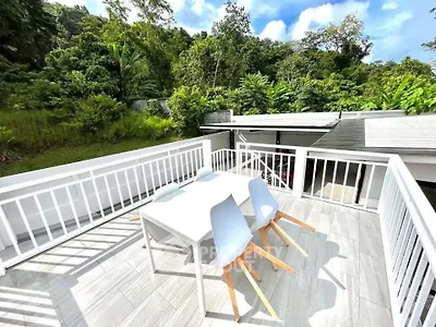 Spacious balcony with modern outdoor dining set and lush green views.