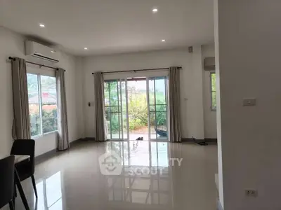 Spacious living room with large windows and garden view, perfect for natural light lovers.
