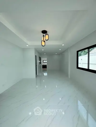 Spacious modern living room with elegant lighting and large windows, perfect for natural light.
